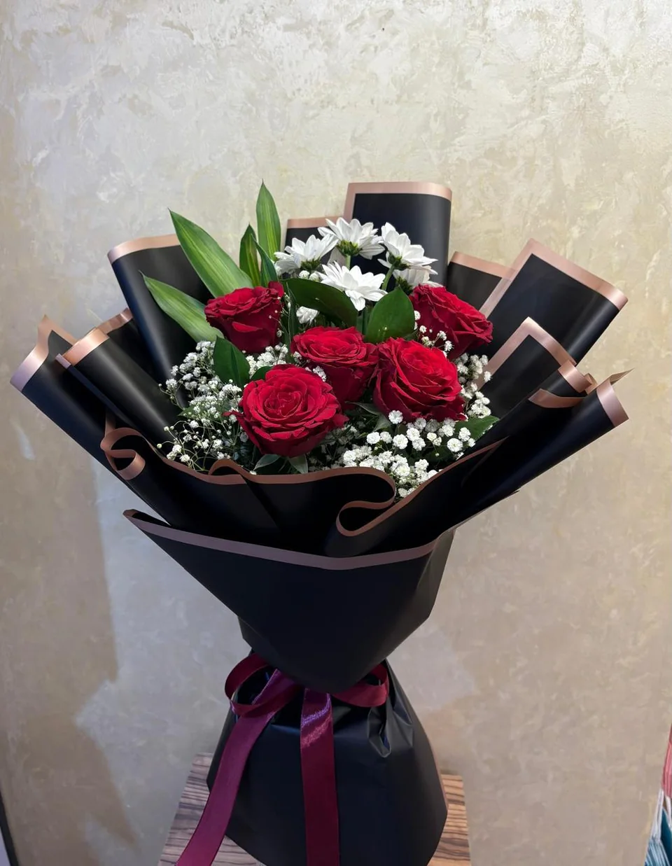Black-wrapped mixed bouquet with red roses and pink and white flowers