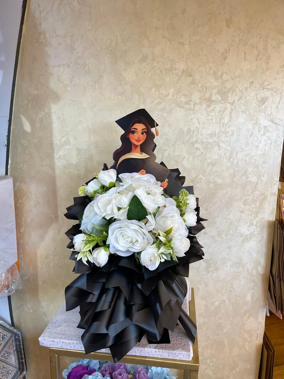 Black and white graduation bouquet with a graduate character topper