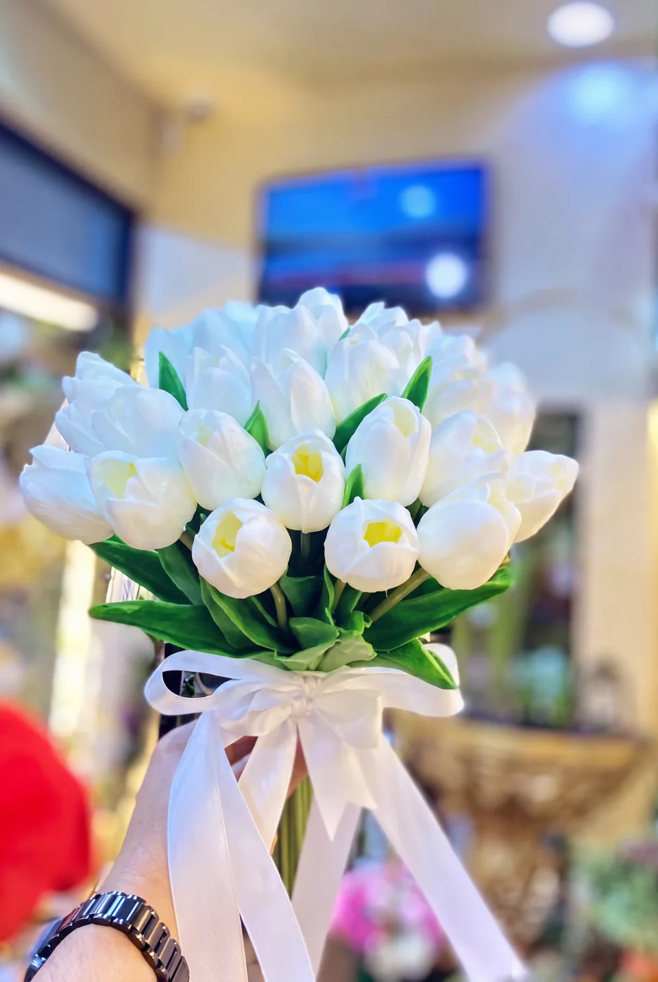 Hand-tied white tulip bridal bouquet with flowing white ribbons