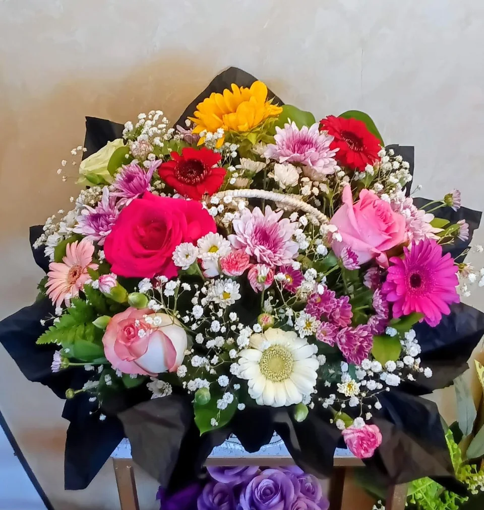 Bright mixed flower basket with pink, red and white blooms and baby's breath