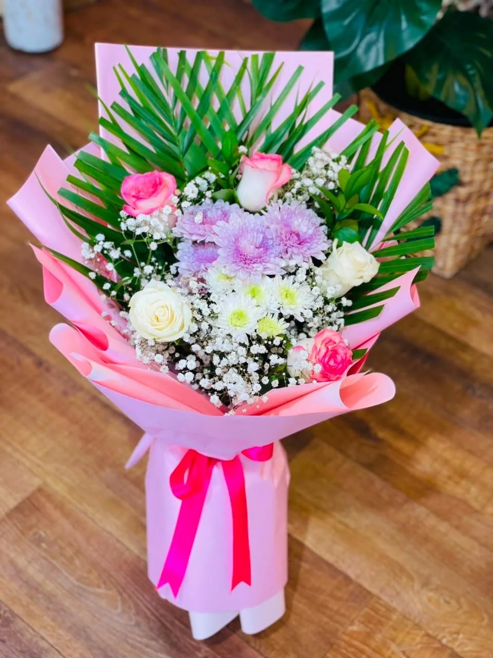 Pastel pink and white bouquet with palm leaves and pink wrapping