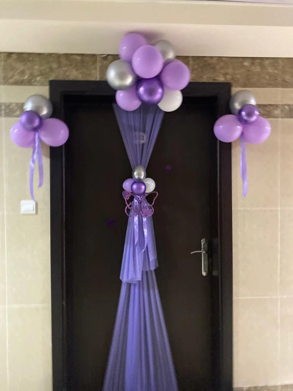 Celebration doorway decorated with purple draping and balloon clusters