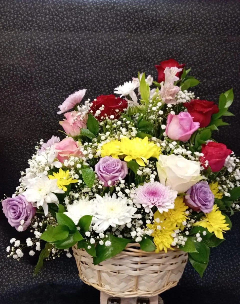 Colorful wicker flower basket with mixed roses and daisies