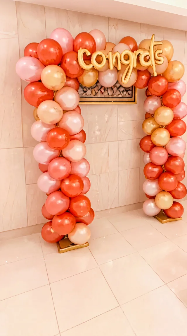 Peach and pink congratulatory balloon arch with a large Congrats sign
