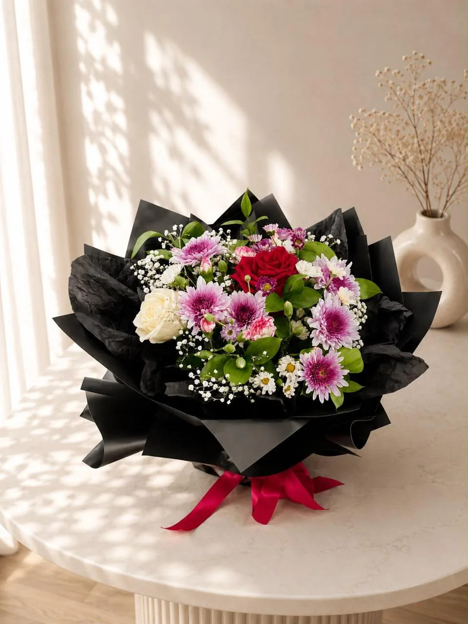 Dark blush bouquet with deep pink roses, white daisies and black wrapping