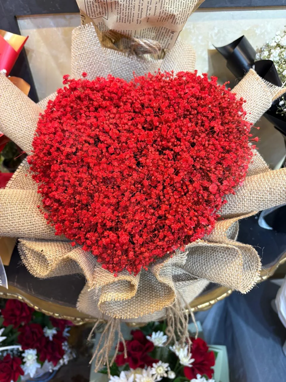 Large heart-shaped bouquet of red dried flowers with gold wrapping