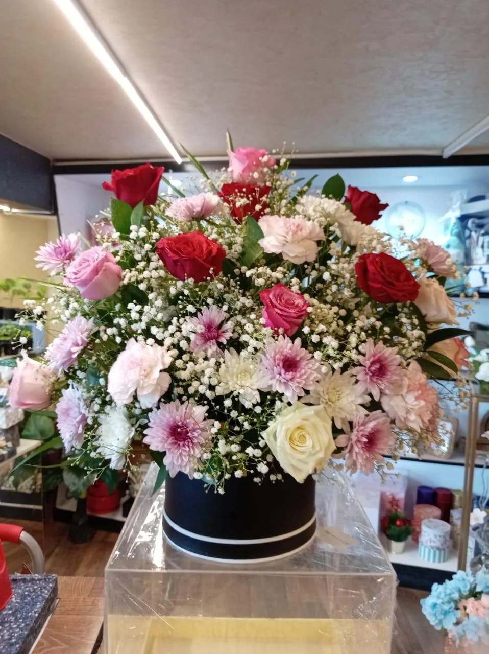 Large round black flower box with a domed mix of pink, red and white blooms