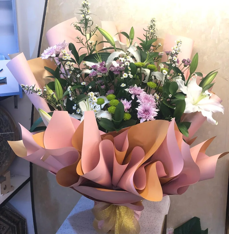 Large mixed bouquet with pink, purple, red and white flowers in peach wrapping