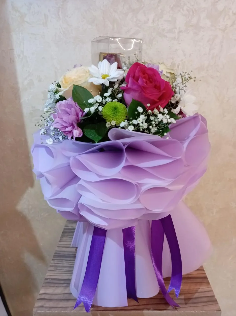 Pink and purple bouquet with white flowers and greenery in purple wrapping