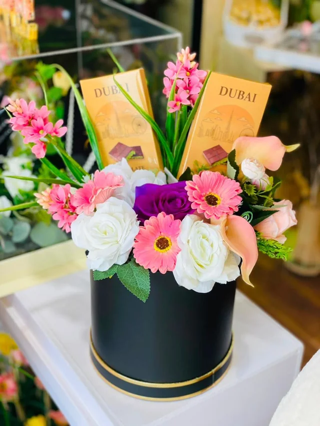 Black flower box with mixed pink and white blooms and wrapped chocolate bars