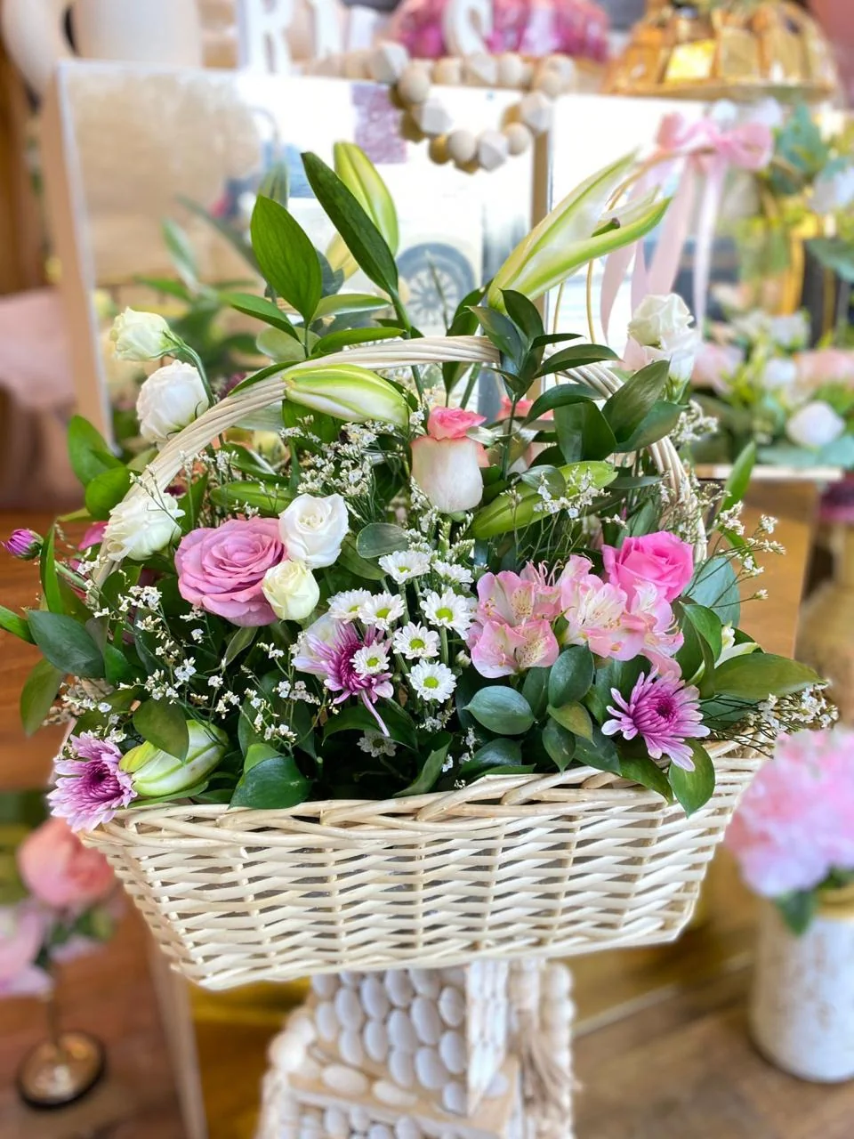 White wicker garden basket with pink and white flowers, lilies and greenery
