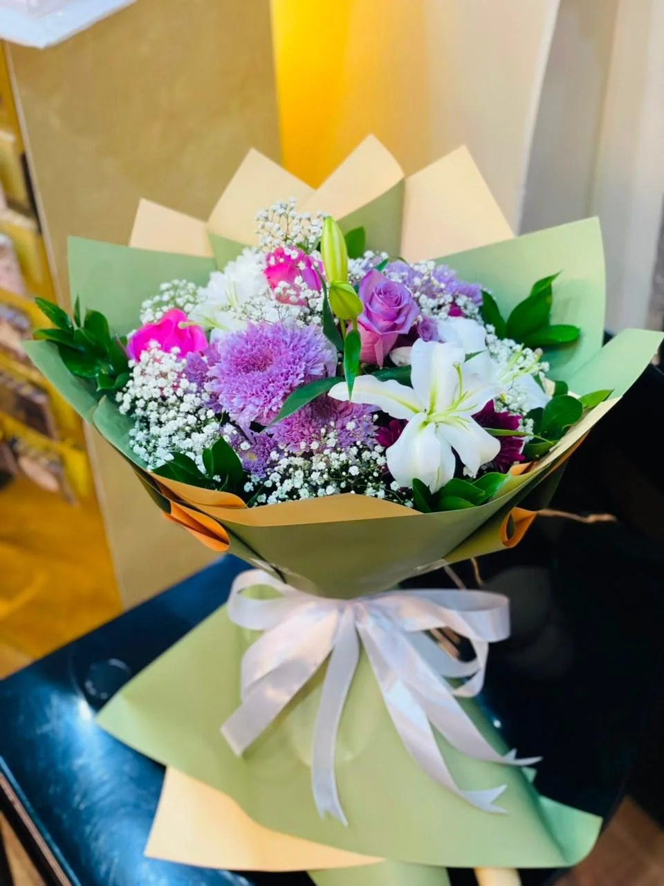 Green-wrapped recovery bouquet with white lilies and pink, purple and white flowers