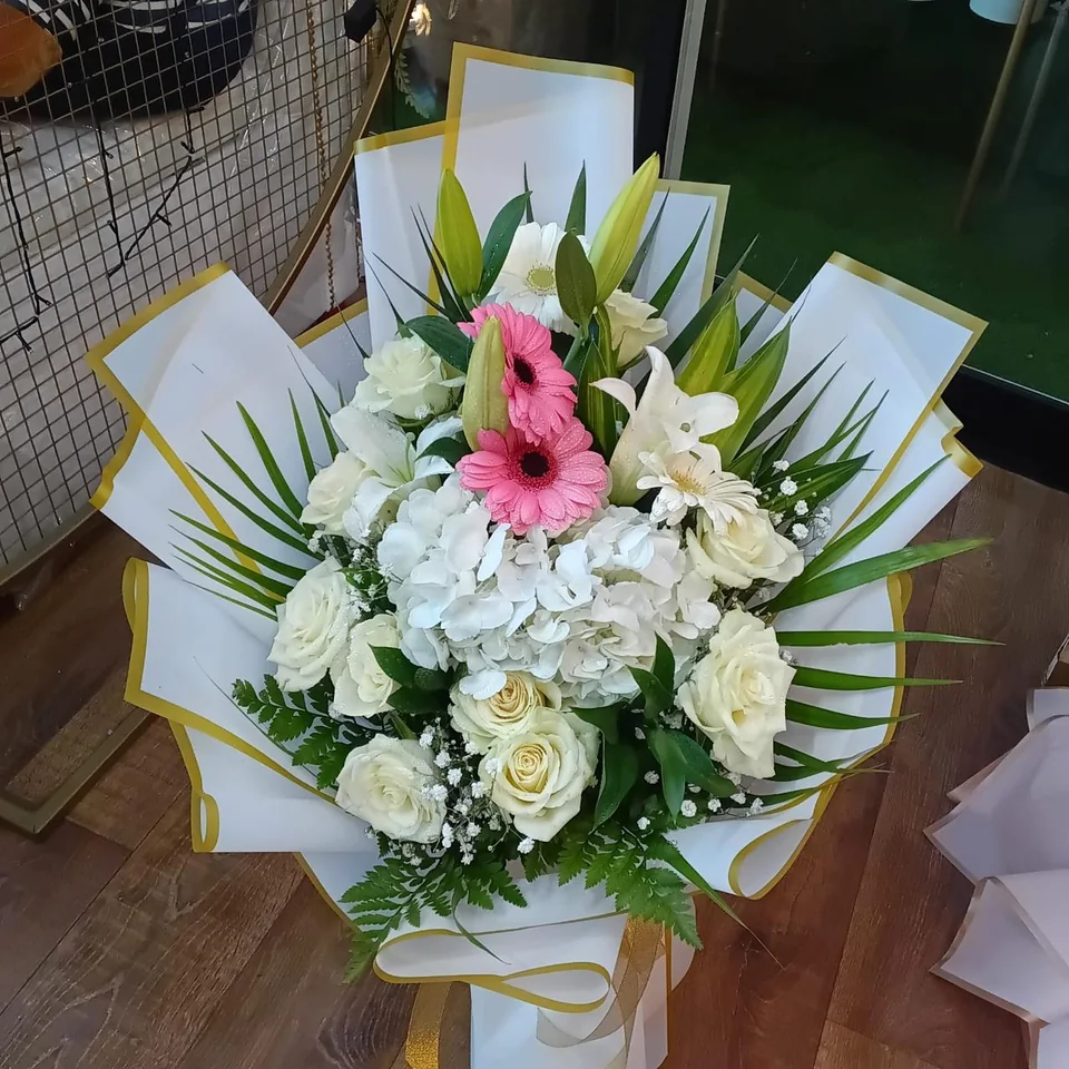White and pink bouquet with lilies, roses, hydrangea and gold-edged wrapping