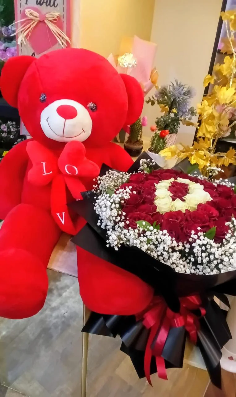 Giant red and white love bouquet beside an oversized red teddy bear