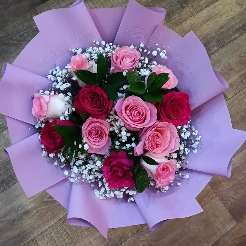 Lilac-wrapped bouquet with pink, red and lilac roses and baby's breath