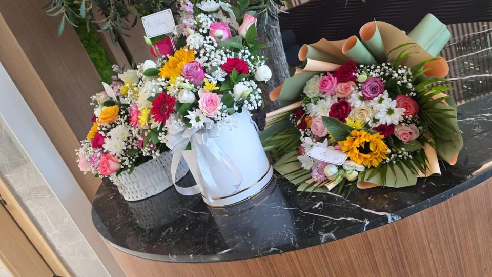 Display of three mixed flower arrangements in baskets, a round box and wrapping