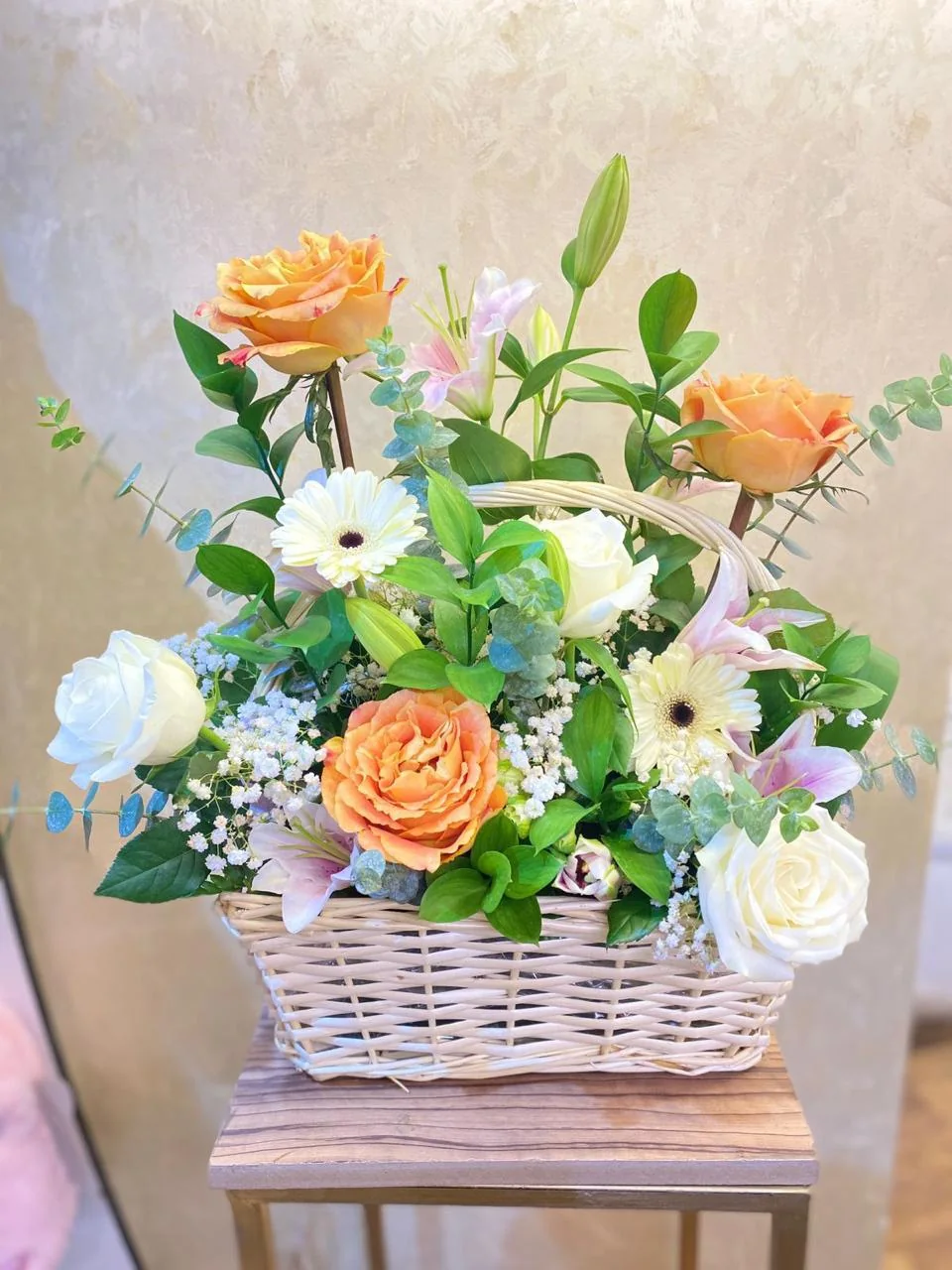 Peach and white flower basket with roses, daisies and greenery