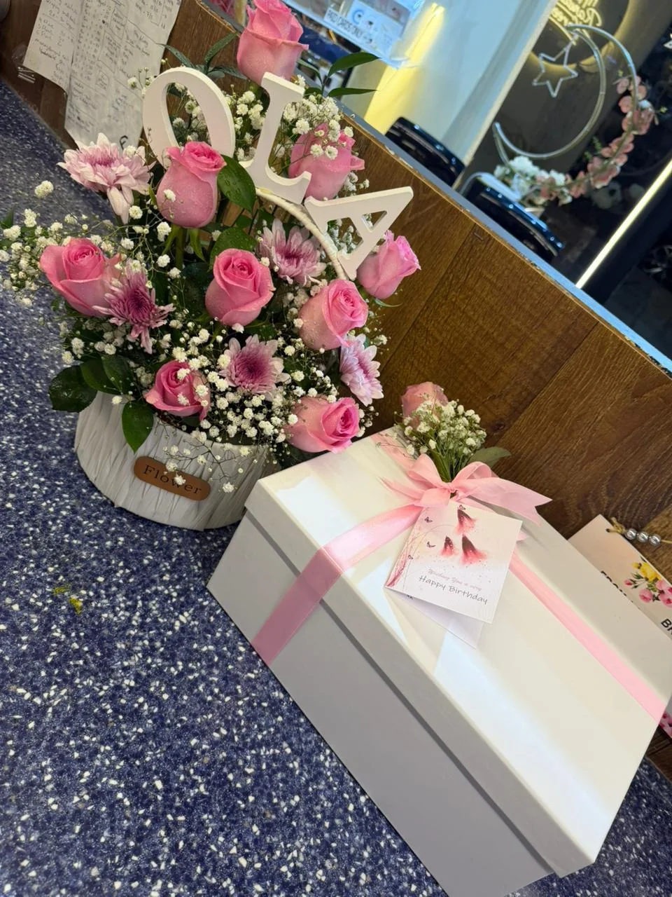 Personalized pink flower arrangement with an initial, wrapped gift box and birthday card