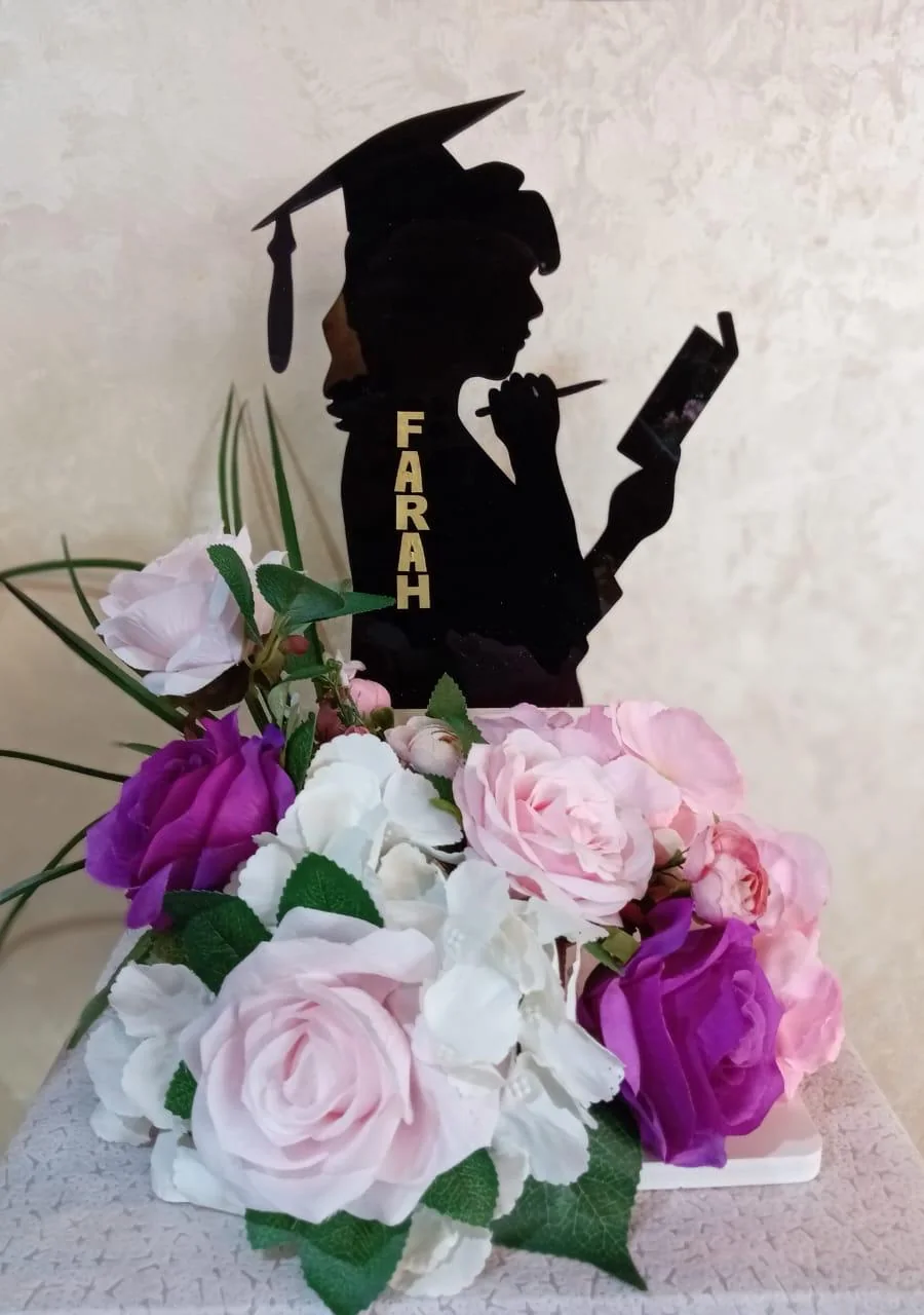 Personalized graduation stand with a named graduate silhouette and pink-purple flowers