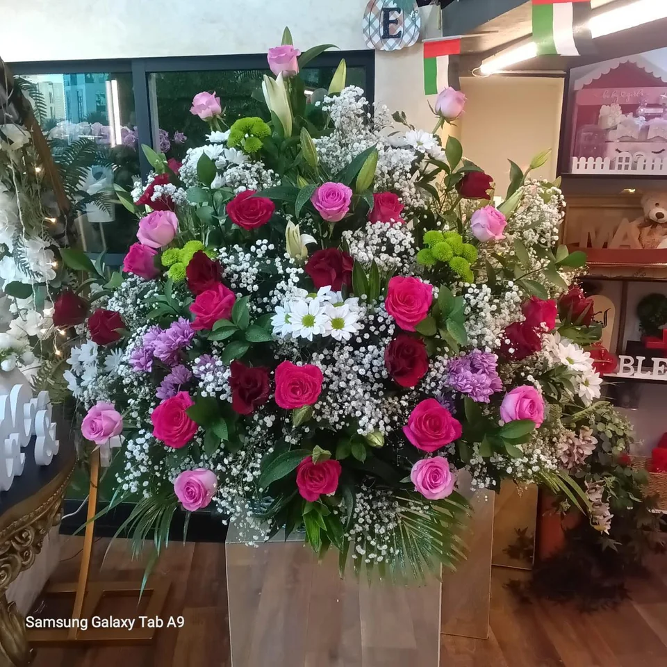 Large wedding flower stand with pink and burgundy roses, white flowers and greenery