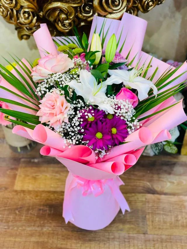 Pink paradise bouquet with lilies, roses, daisies and palm leaves