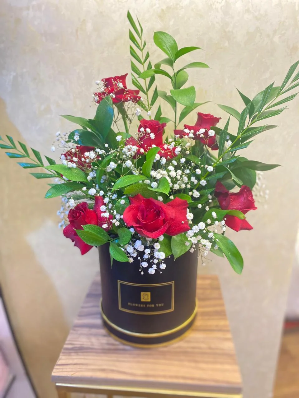 Black romantic flower box with red roses, white filler flowers and greenery