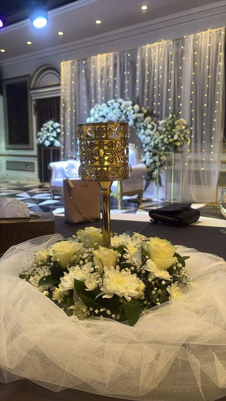 Royal wedding table centerpiece with white flowers, tulle and a gold candle holder