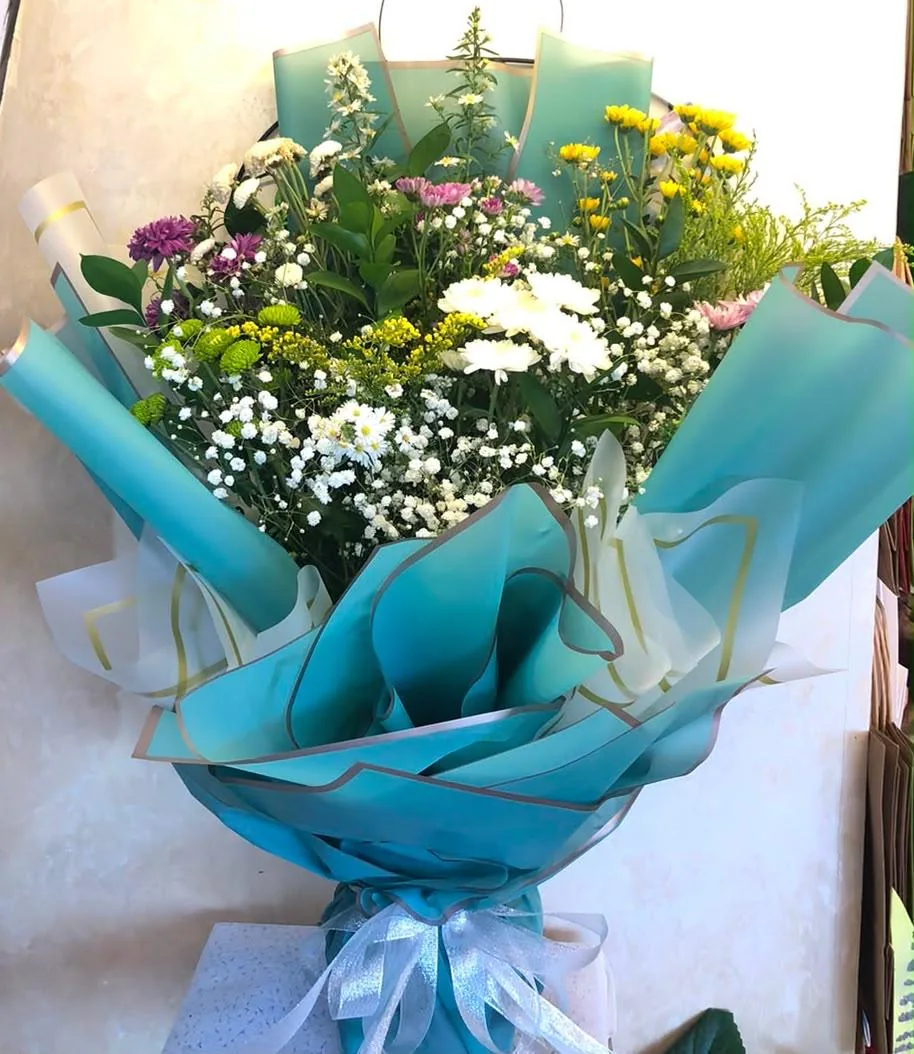Secret garden bouquet with yellow and white flowers in blue-green wrapping