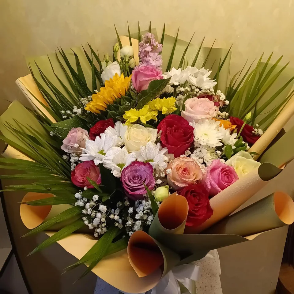 Bright mixed recovery bouquet with yellow, pink, red and white flowers and palm foliage
