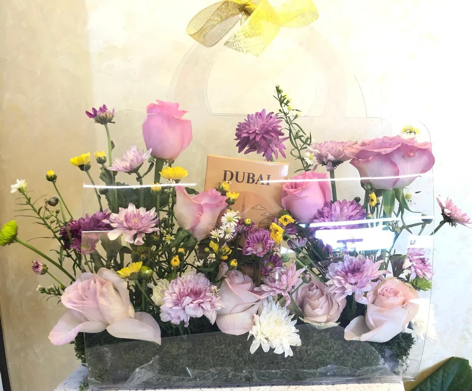 Transparent handled flower bag with pastel blooms and Dubai chocolate bars