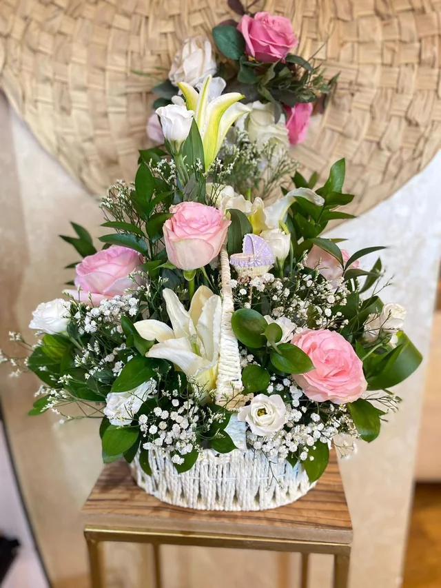 Welcome-baby flower basket with pink and white roses, lilies and a baby-carriage ornament